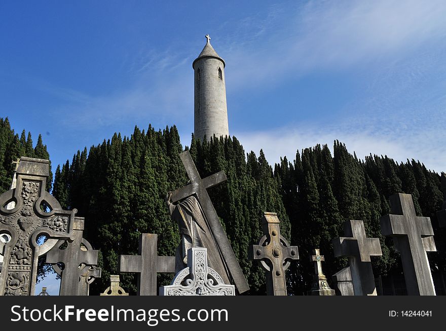 Image of a graveyard in dublin ireland with celtic cross headstones and cemetery tower in background