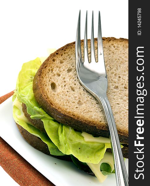 Dark bread sandwich with standing fork, isolated on white background