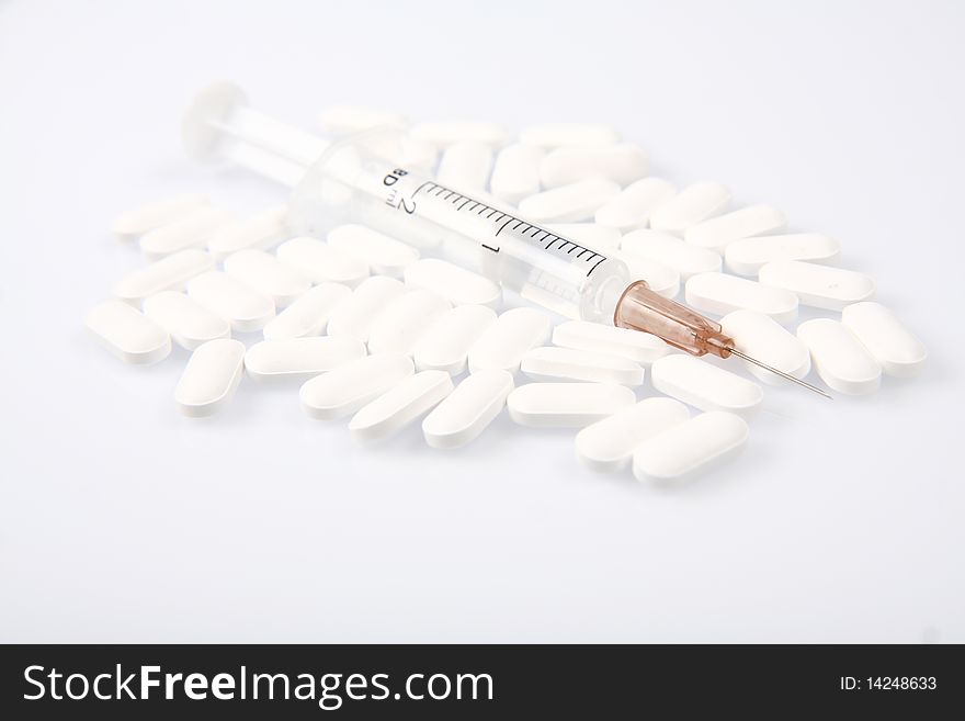 Syringe surrounded by white pills on white background. Syringe surrounded by white pills on white background