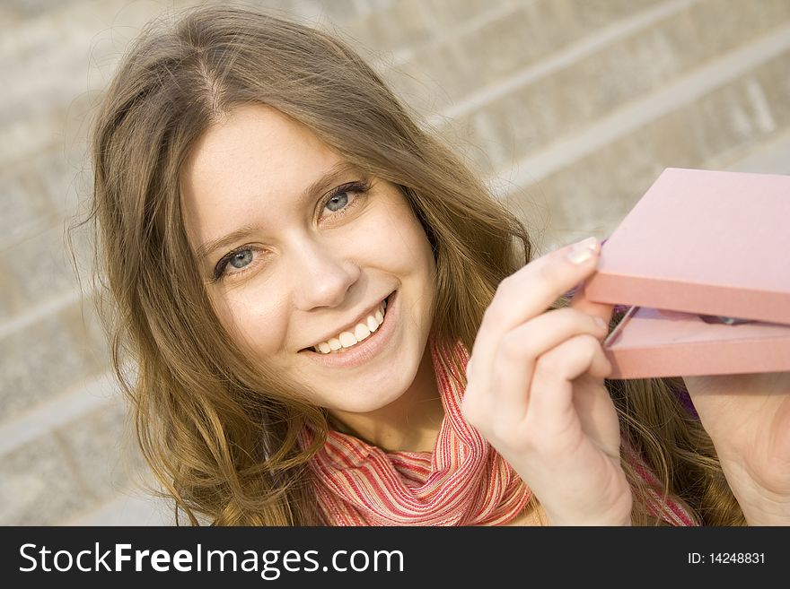 Young woman sitting on the stairs to the street, and holds a pink gift box. Young woman sitting on the stairs to the street, and holds a pink gift box