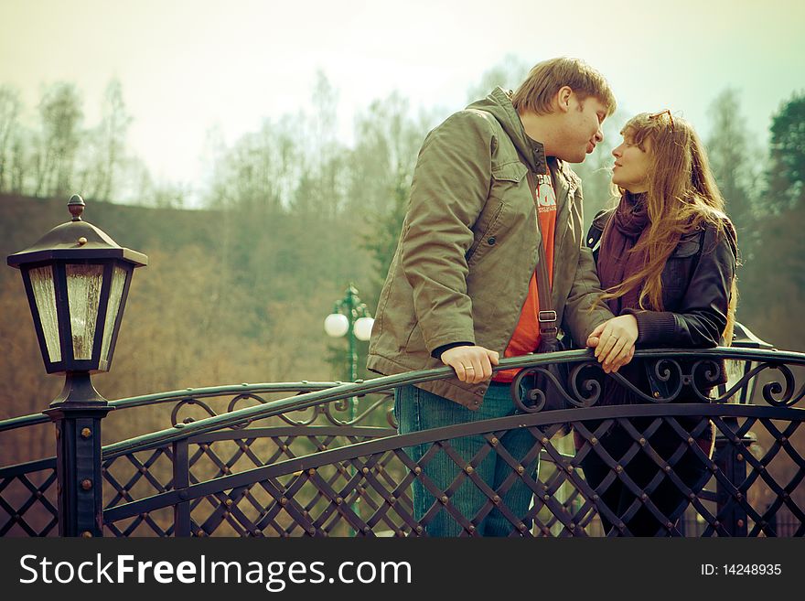 Romantic couple standing on a bridge, they are going to kiss each other. Romantic couple standing on a bridge, they are going to kiss each other