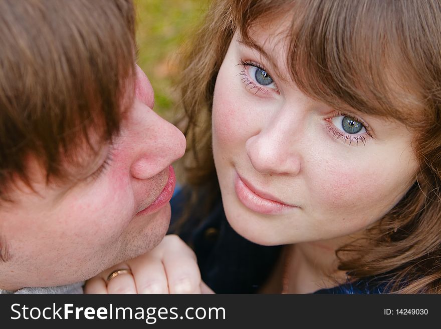 Close-up portrait of a young beautiful wife and her husband, he is looking at her. Close-up portrait of a young beautiful wife and her husband, he is looking at her