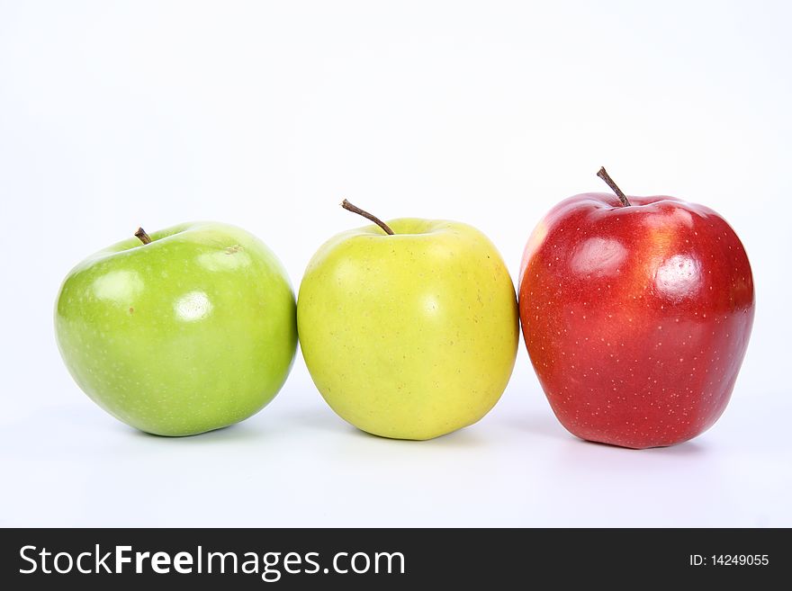 Three apples (green, yellow,red) in a raw on white background