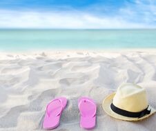 Beach Summer Holiday Background. Flip Flops And Hat On Sand Near Ocean. Summertime Accessories On Seaside. Tropical Vacation Stock Photos Beach Summer Holiday Background. Flip Flops And Hat On Sand Near Ocean. Summertime Accessories On Seaside. Tropical Vacation Stock Photos