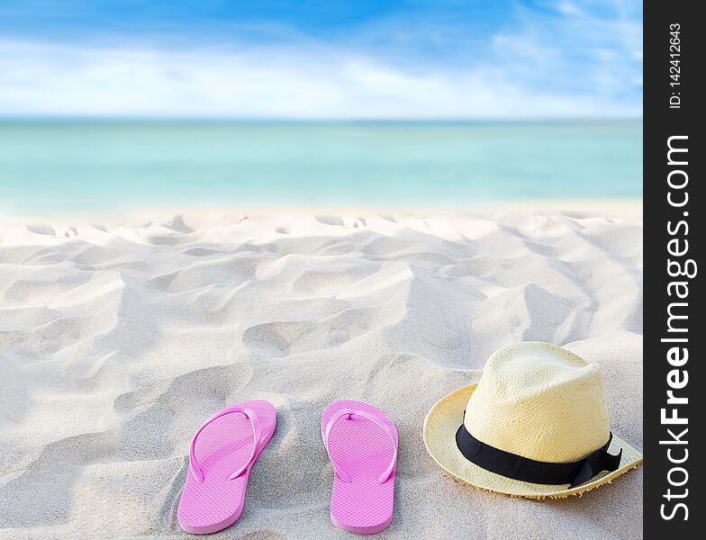 Beach summer holiday background. Flip flops and hat on sand near ocean. Summertime accessories on seaside. Tropical vacation and relax travel concept. Top view and copy space. Selective focus