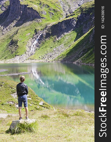 A boy watching the lake called Nassfeld Speicher in Hohe Tauern National Park in Austria. A boy watching the lake called Nassfeld Speicher in Hohe Tauern National Park in Austria