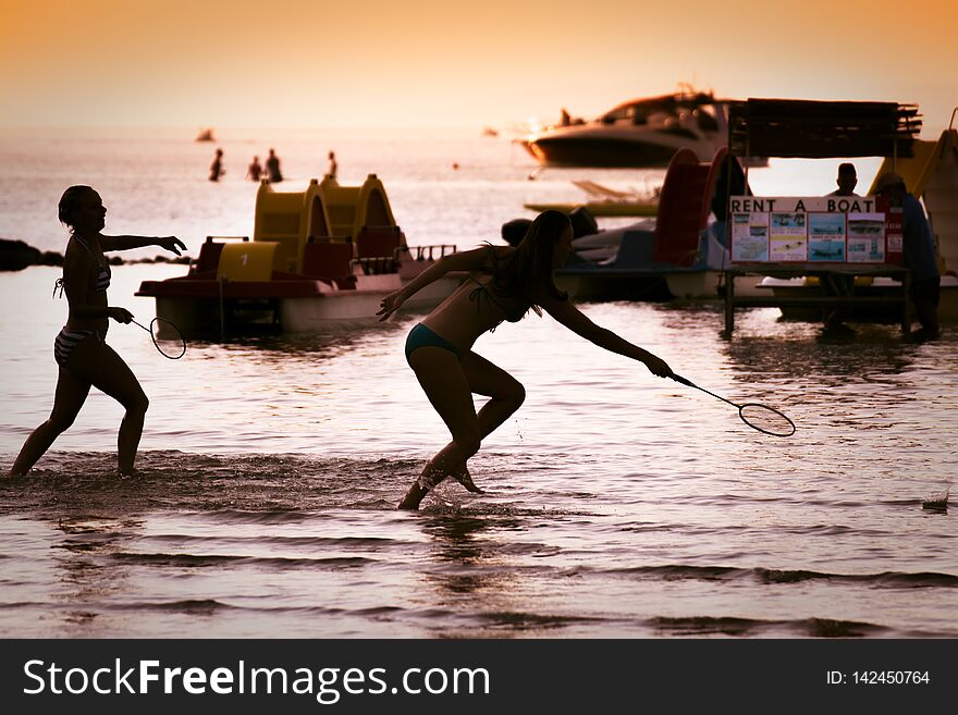 Backlit girls playing badminton on the beach,. Backlit girls playing badminton on the beach,