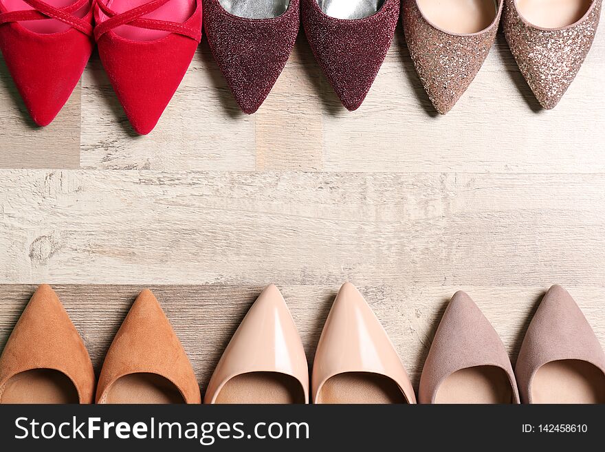Stylish high heeled shoes on wooden floor, flat lay