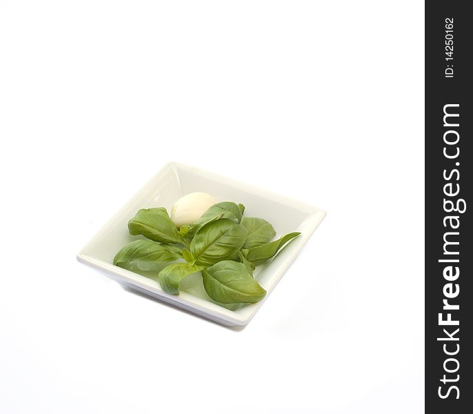 Bowl with garlic and basil on a white background