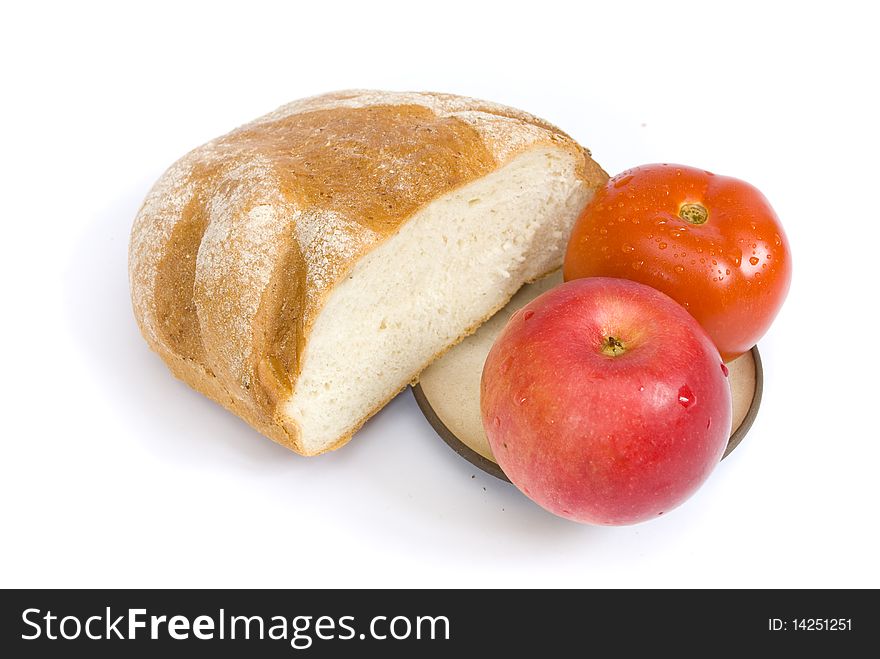 White bread, dusted with flour, red tomato and ripe apple covered with drops of water, on a plate, on a white background. White bread, dusted with flour, red tomato and ripe apple covered with drops of water, on a plate, on a white background