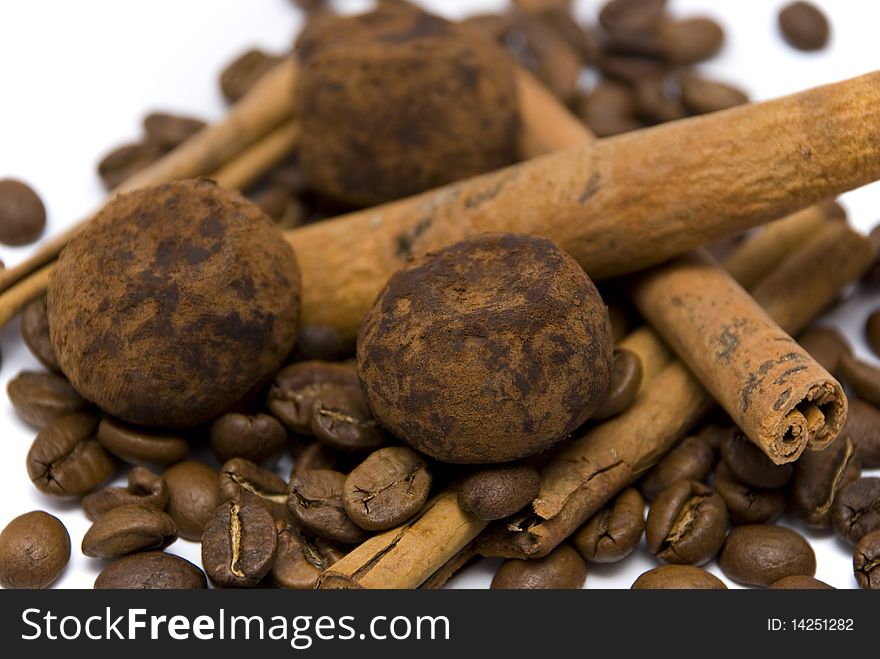 Coffee beans, chocolate truffles and cinnamon sticks on the white background, shallow depth of field. Coffee beans, chocolate truffles and cinnamon sticks on the white background, shallow depth of field