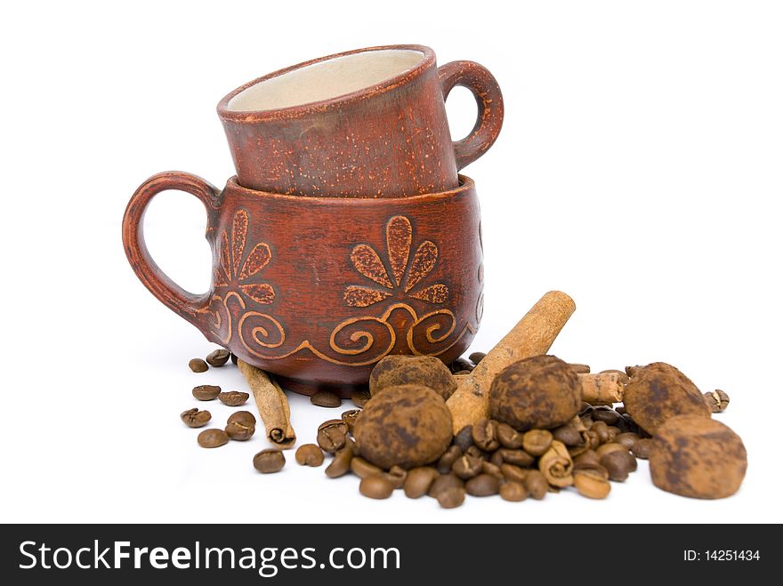 Two ceramic cups red, fragrant coffee beans, sweets, chocolate truffles and cinnamon sticks isolated on white background. Two ceramic cups red, fragrant coffee beans, sweets, chocolate truffles and cinnamon sticks isolated on white background