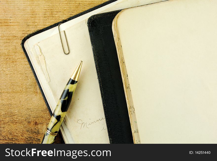 Close up corner of a vintage notebook and pen on a rustic wooden table.