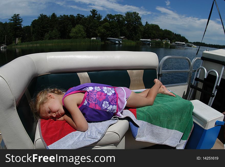 A young girl rests in the sunshine on a boat as it goes for a spin around a lake. A young girl rests in the sunshine on a boat as it goes for a spin around a lake.