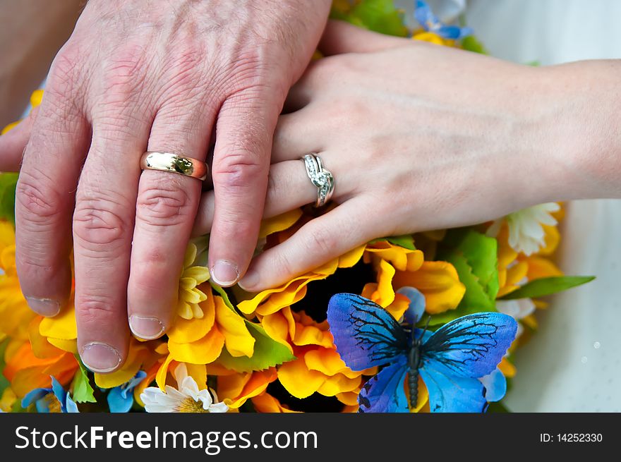 Man and woman holding hands over bouquet of flowers. Man and woman holding hands over bouquet of flowers