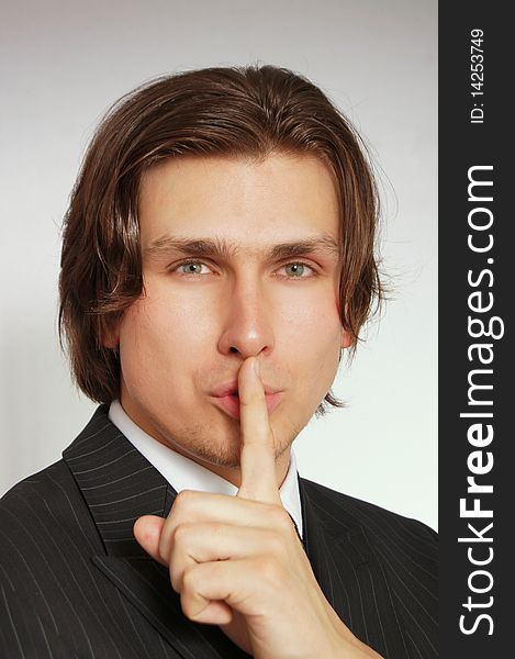 Young man holding finger over mouth gesturing silence. Young man holding finger over mouth gesturing silence