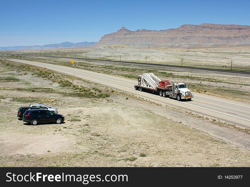An American style truck carrying an oversized load travelling ona highway through the desert in Utah USA. An American style truck carrying an oversized load travelling ona highway through the desert in Utah USA.