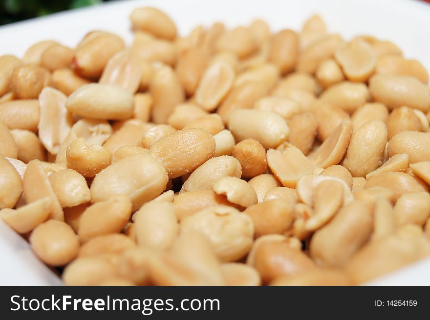 Roasted and salted peanuts on white bowl