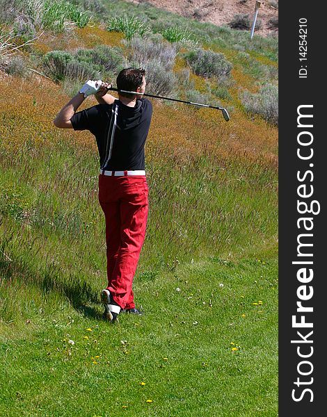 Young golfer playing a shot from the semi-rough