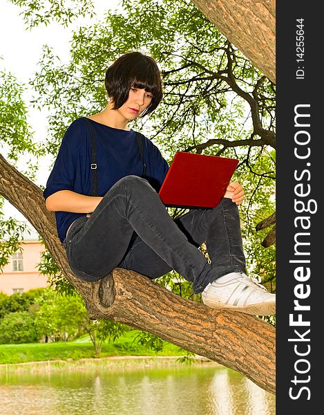 Young woman with notebook sitting on tree. Young woman with notebook sitting on tree