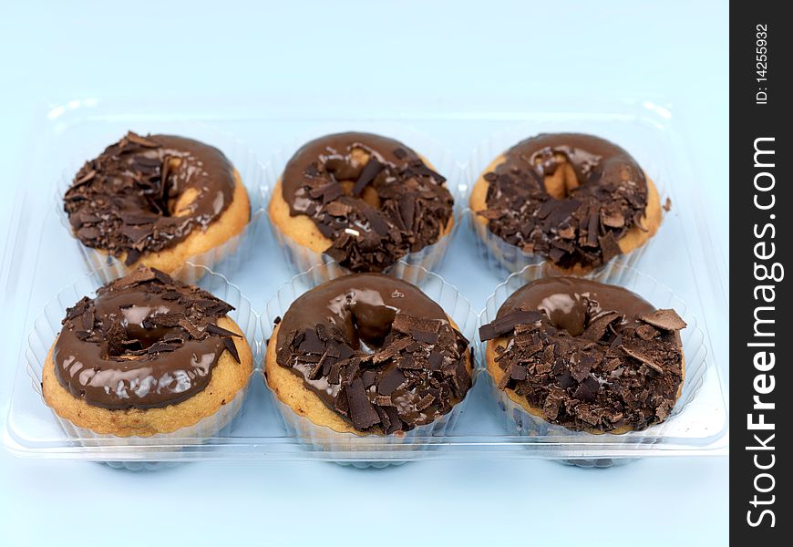 Chocolate donuts in a tray isolated against a blue background