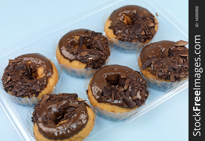 Chocolate donuts in a tray isolated against a blue background