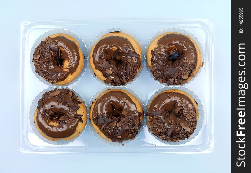 Chocolate donuts in a tray isolated against a blue background