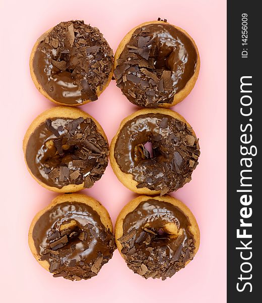 Chocolate donuts in a plate isolated against a pink background