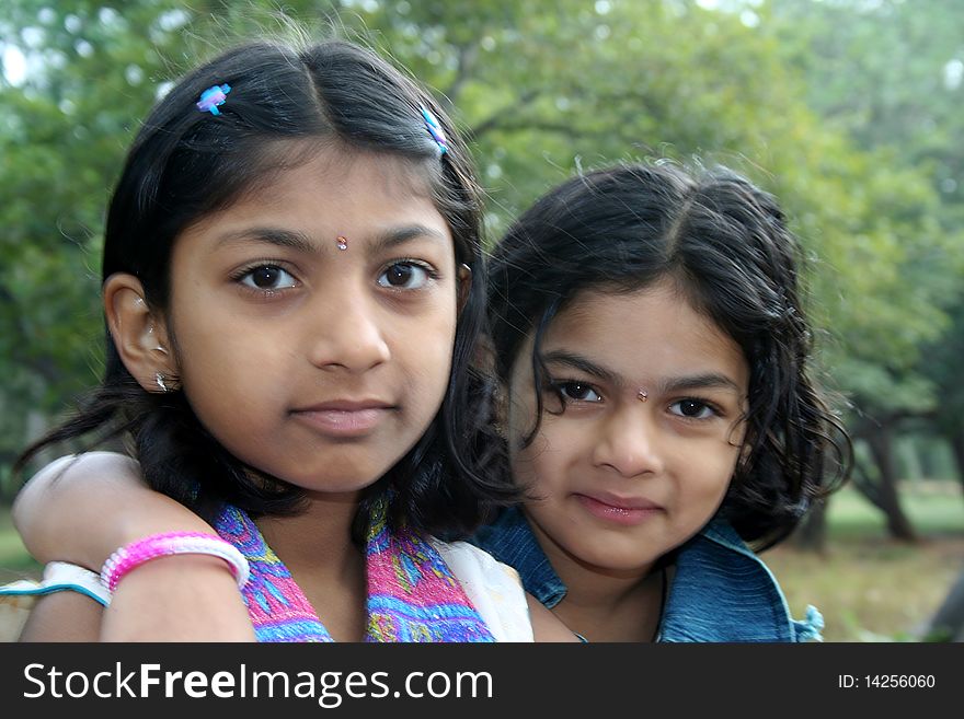 Younger sister affectionately putting her arm over the shoulder of her elder sister. Younger sister affectionately putting her arm over the shoulder of her elder sister