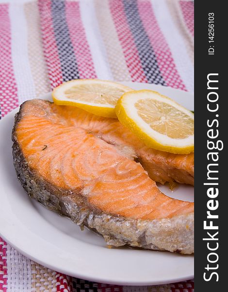 Grilled salmon with lemon on a white plate