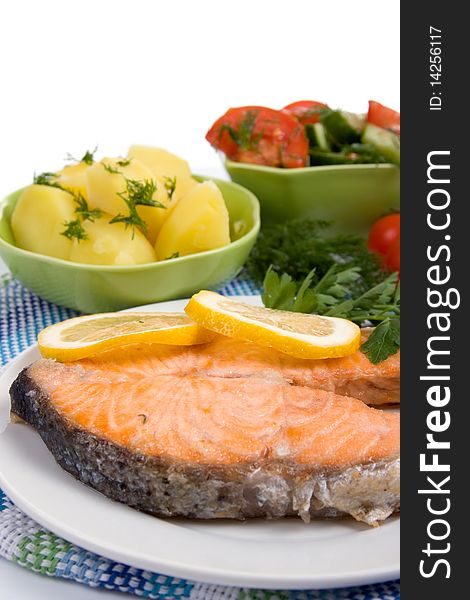 Grilled salmon with potatoes and salad on a white background