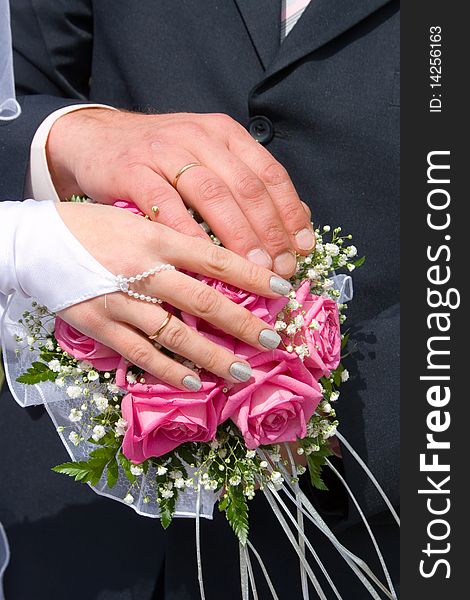 Hands newlyweds on the wedding bouquet