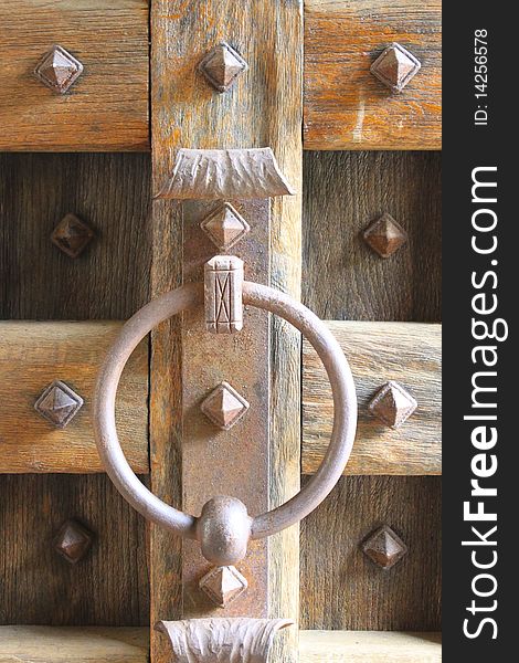 A Medieval Door Knocker comes in iron on a grand wooden door.