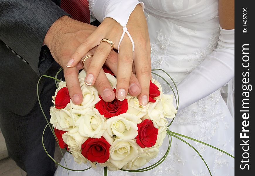 Newly married - hands with gold rings on a beautiful wedding bouquet