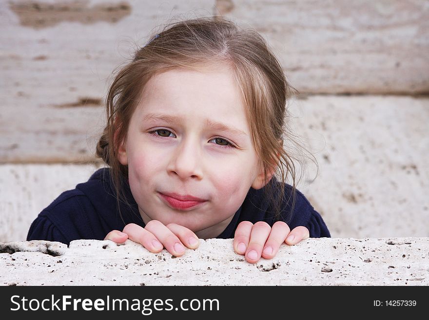 Pretty little girl behind the stone wall. Pretty little girl behind the stone wall