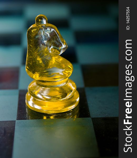 Knight a glass chess piece with glass Chess board in the background.The knight is the next piece on the board. In olden times, knights were wealthy individuals. On the chessboard, the knights are placed on either side of the bishops, showing their place in terms of wealth and importance. You can only move a knight in an L-shape.  The knight is the only piece on the board that may jump over other pieces. The knight moves two squares horizontally or vertically and then one more square at a right-angle. The knight&#x27;s move is shaped like an â€œLâ€. The knight always lands on a square opposite in colour from its initial square.