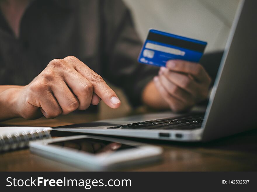 Businessman holding credit card and typing on laptop for online shopping and payment makes a purchase on the Internet, Online