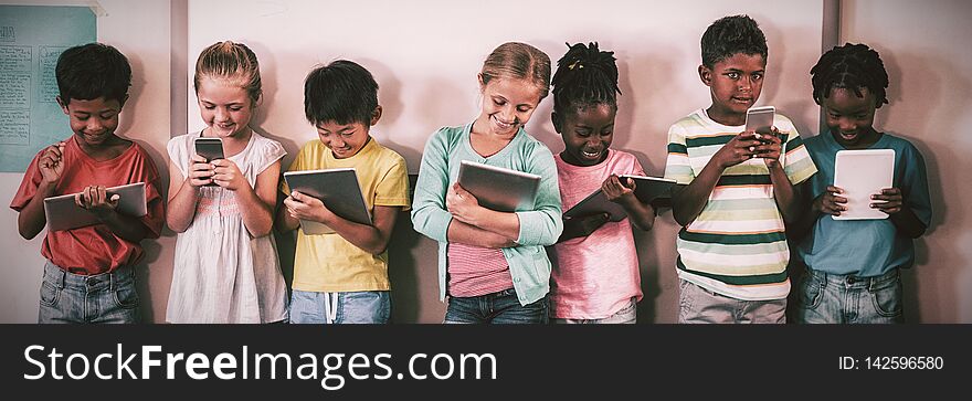 Happy pupils standing with technology