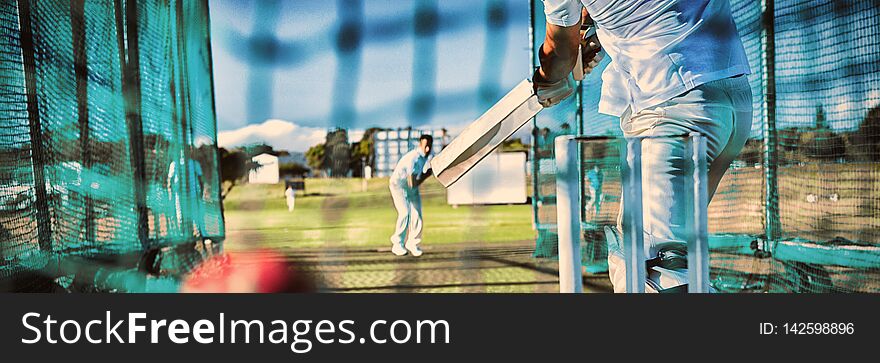 Low section of sportsman playing cricket at field on sunny day