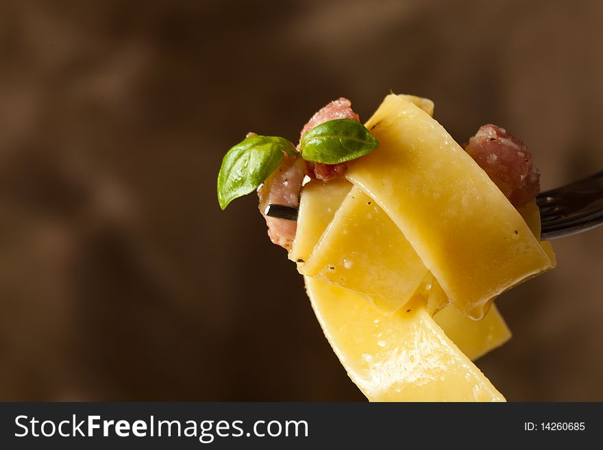 Photo of pasta with bacon on a wood table with a brown background