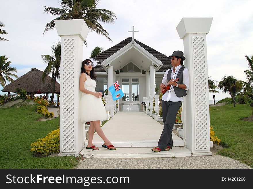 A happy couple posting in front of a chapel, they are going to get married.