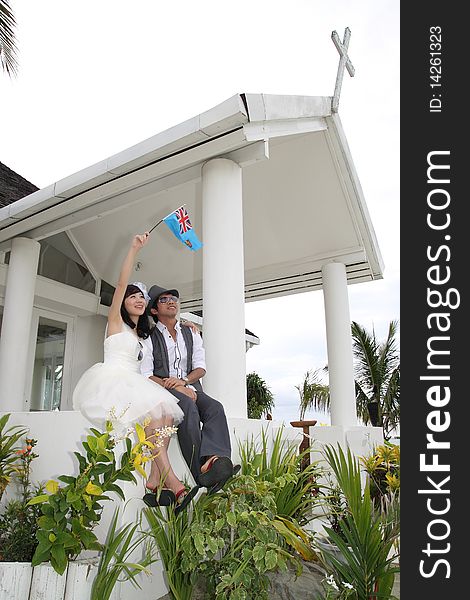 A happy couple posting in front of a chapel, they are going to get married.