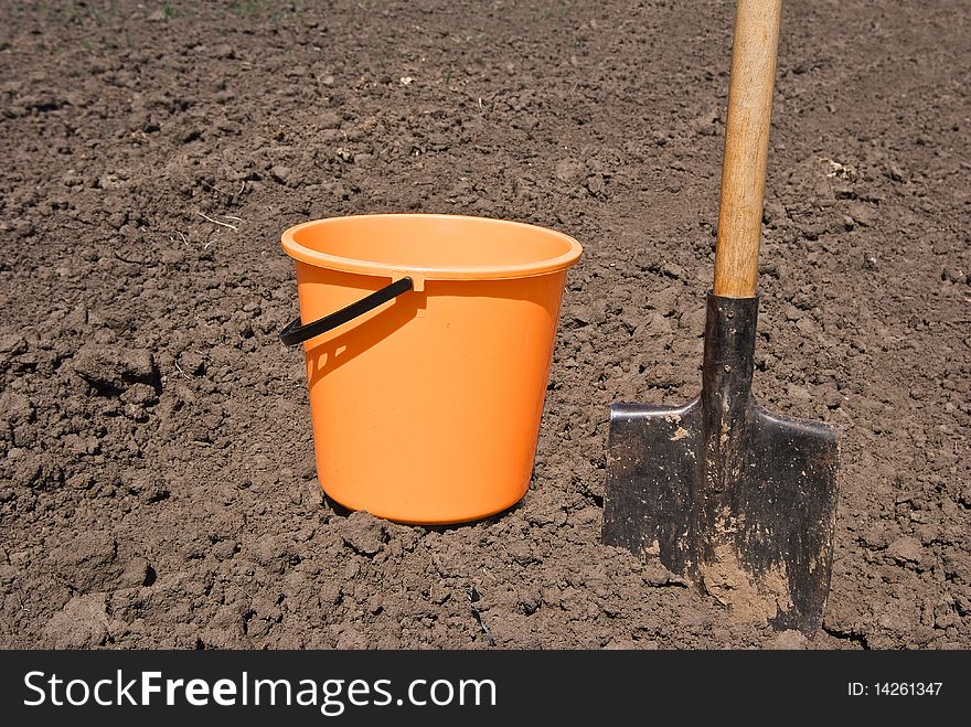 Orange bucket and shovel on a field