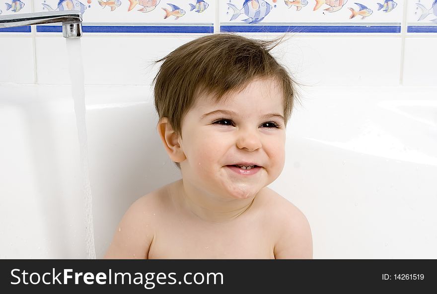 Infant child is sitting in the bath tub. Infant child is sitting in the bath tub