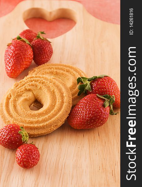 Strawberries with cookies on wooden board