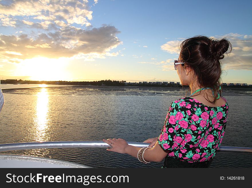 An Asian girl is appreciating the charming sunset on a yacht. An Asian girl is appreciating the charming sunset on a yacht.