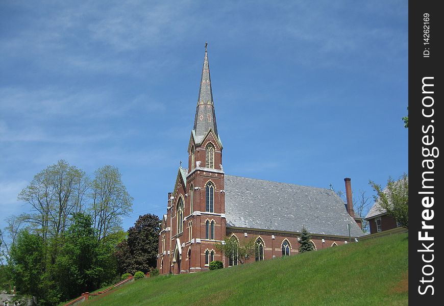 A beautiful Catholic Church sits high on a hill in Vermont against the deep blue sky. A beautiful Catholic Church sits high on a hill in Vermont against the deep blue sky