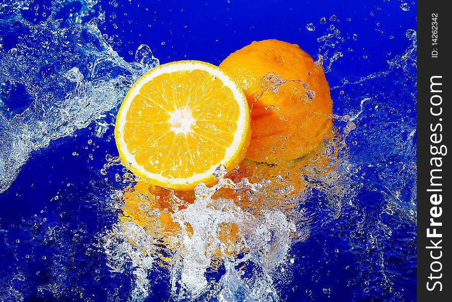 Fresh orange in a spray on a blue background