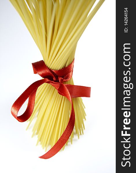 Bunch of spaghetti tied with a red ribbon isolated on white background - focus on red ribbon. Bunch of spaghetti tied with a red ribbon isolated on white background - focus on red ribbon.