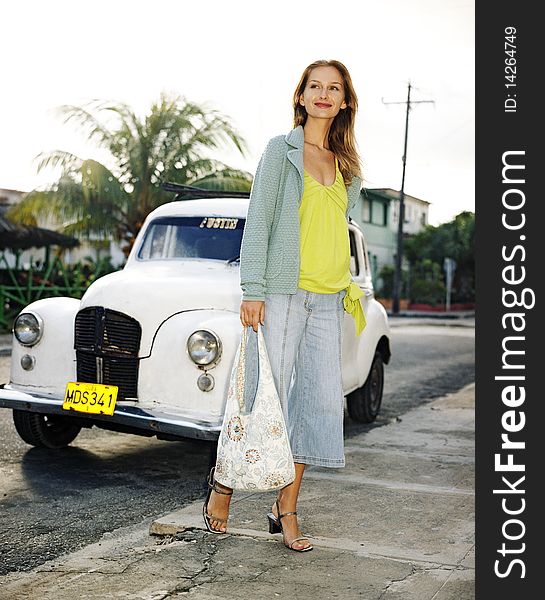 Beautiful young woman by an old historic cars on the street